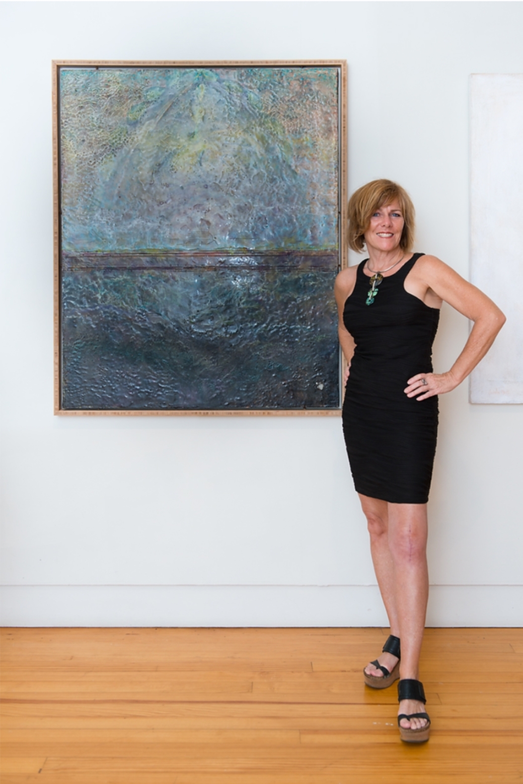 Gayle Barklie standing beside one of her large encaustic paintings